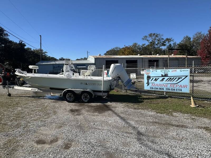 Bay boat with a Mercury outboard on its trailer outside the fenced boat yard