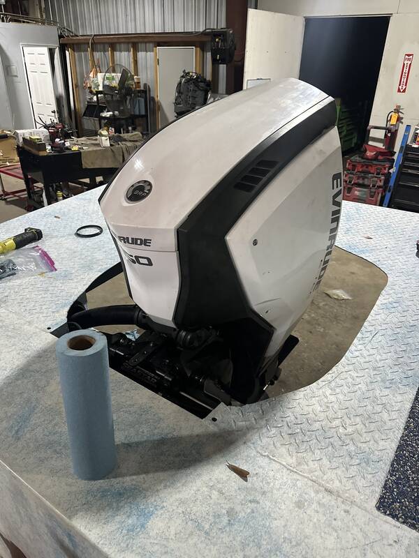White Evinrude outboard set in a diamond-plate deck panel inside the repair shop