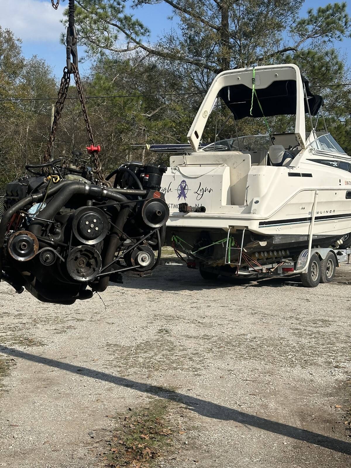 Inboard engine lifted out of a cabin cruiser on a chain hoist in the boat yard