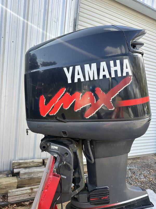 Black Yamaha VMAX outboard on a red stand against the shop wall
